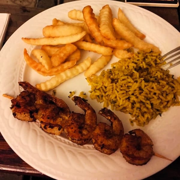 Grilled shrimp skewer, crinkle-cut fries, and yellow rice on a white plate at America's Best Wings.