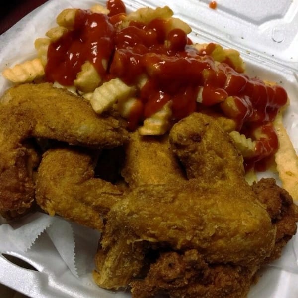 America's Best Wings' fried chicken wings and crinkle-cut fries with ketchup in a takeout container.